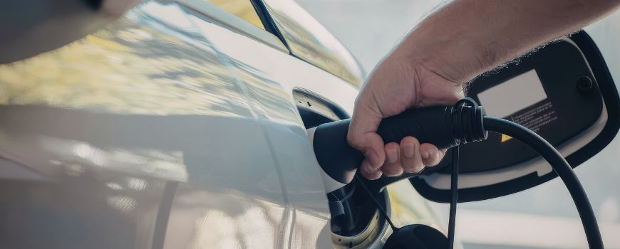 A person charging their car with an EV charging cable.